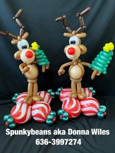 two plastic reindeer figurines standing on top of christmas balls with candy canes