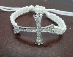 "Beautiful thick nylon cord metal rhinestone cross bracelet. With a square knot pattern .  This bracelet is adjustable with a pull closure. Ends will dangle slightly . Thick intricate  rhinestone cross as the center focal.  Cross measures  Bracelet goes from 7\" to 9\"  1 3/8\" long 1 1/2 \" wide I do ship world wide . Please message me for a quote if you don't see your shipping ." Adjustable Cross Pendant Jewelry, Adjustable Cross Jewelry With Adjustable Cord, Adjustable Cross Jewelry With Cord, Adjustable Cross-shaped Jewelry With Cord, White Adjustable Cross-shaped Jewelry, Creative Bracelets, Knot Pattern, Square Knot, Rhinestone Cross