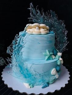 a three tiered cake with blue frosting and seashells