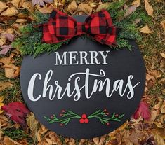 a merry christmas sign on the ground with leaves around it and a red bow tie