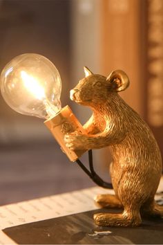 a gold colored bear holding a light bulb