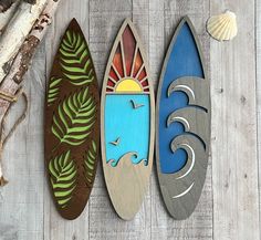 three surfboards are hanging on the wall next to shells and seashells,