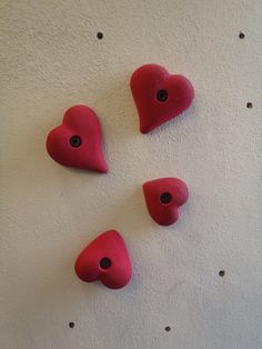 three red heart shaped buttons on a white wall