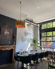 the dining room is set with black chairs and white brick walls, along with a chandelier that hangs from the ceiling