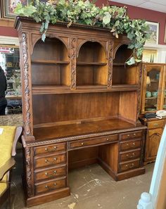 an old wooden desk with green plants growing on it's top and bottom shelf