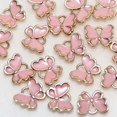 pink and gold butterfly shaped charms on a white surface with the word love written in it