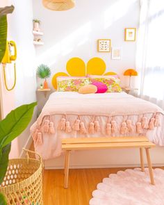 a bedroom with pink bedding and yellow headboard