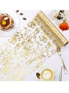 a table topped with gold confetti next to a cup of coffee and pastry