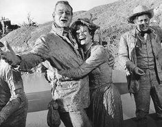 an old black and white photo of three men in mud suits with their arms around each other