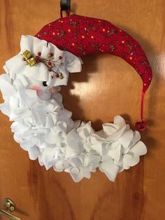 a wreath made out of white ruffles and a red hat on a door