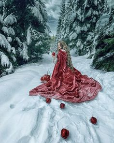 a woman in a red dress sitting on snow covered ground