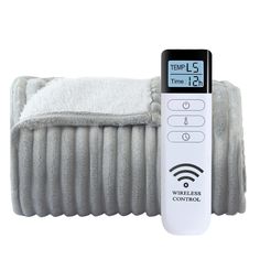 a remote control sitting on top of a pile of gray blanketed blankets next to an alarm clock