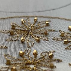 a gold snowflake is shown on a white tablecloth with golden chains and cubes