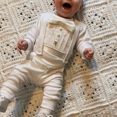 a baby laying on top of a white crocheted blanket with his mouth open