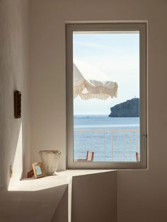 an open window overlooking the ocean with a table and chairs