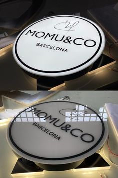 two signs that are hanging from the ceiling in front of a window and one has a sign for momu & co barcelona on it