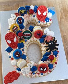 a cake made to look like the letter o is decorated with spiderman and other characters