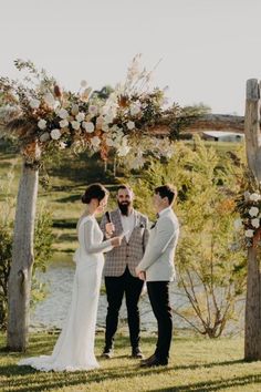 a bride and groom are standing under an arch with flowers on the altar for their wedding ceremony