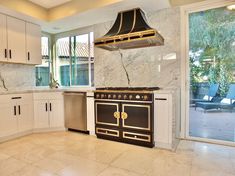 a kitchen with marble counter tops and an oven in the center, surrounded by white cabinets