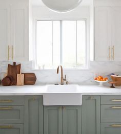 a kitchen with green cabinets and white counter tops, gold handles on the faucet