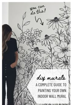 a woman standing in front of a wall with flowers on it and the words diy murals