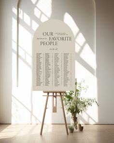 a white sign sitting on top of a wooden easel next to a potted plant