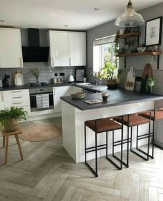 a kitchen with white cabinets and black counter tops next to a wooden flooring area