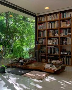 a living room filled with lots of books on top of a wooden book shelf next to a window