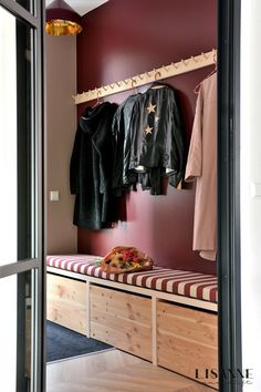 an open closet with clothes hanging on the rack and coat racks in front of it