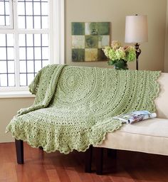 a green crocheted blanket sitting on top of a couch next to a window