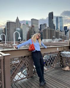 a woman standing on top of a bridge in front of a large cityscape