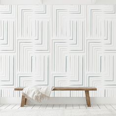 a wooden bench sitting in front of a wall with white and blue lines on it