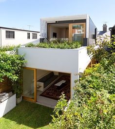 a small house with plants growing on the roof