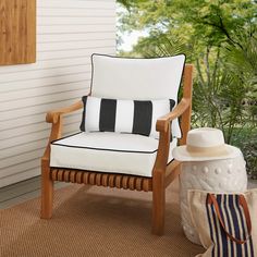 a yellow chair sitting on top of a rug next to a white wall and trees