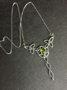 "I've designed this long, statement Celtic inspired necklace entirely in sterling silver featuring a center, faceted 10x8mm peridot gemstone! The frame, or centering, of the pendant is made with Celtic Trinity Knots and sterling wire work braids down the center to add the balancing touches to the piece. It comes with a sterling box chain which is soldered to each end of the pendant. This piece is 18\" in length, including the chain, and the pendant, itself, is approximately 3 inches, in height, Elegant Peridot Jewelry For May Birthstone, Formal Peridot Jewelry For May Birthstone, Elegant Peridot Necklaces For Wedding, Silver Peridot Jewelry For Anniversary, Silver Peridot Jewelry With Gemstone, May Birthstone Jewelry In Silver With Peridot, Silver Peridot Jewelry For May Birthstone, Fine Jewelry Hallmarked Peridot, Handmade Silver Necklace With Peridot