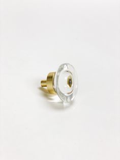 a glass and brass knob on a white surface with a black dot in the middle