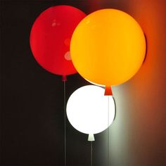 three balloons are hanging in the dark with one light on it's side and another balloon above them