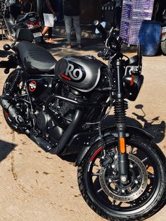 a black motorcycle parked on the side of a road next to other motorcycles and people