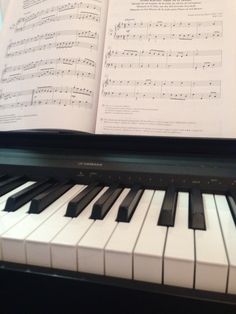 an open book sitting on top of a piano with sheet music in front of it