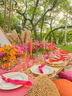 the table is set with pink and orange napkins, place settings, and flowers