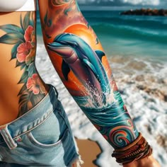 a woman with a dolphin tattoo on her arm next to the ocean and waves in the water