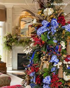 a christmas tree decorated with blue and white flowers, greenery and lights in a living room