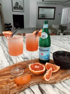 two glasses filled with orange juice and garnished with an orange slice on a cutting board