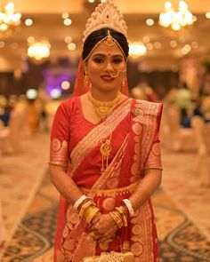 a woman in a red and gold bridal outfit holding a basket with flowers on it