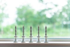 four candles are lined up on a window sill