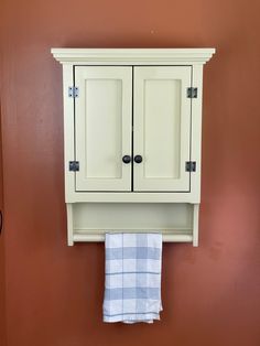 a white cabinet sitting on top of a wall next to a towel rack