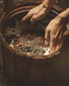 a person is stirring something in a wooden bucket