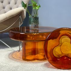 a glass table sitting on top of a white carpeted floor next to a chair