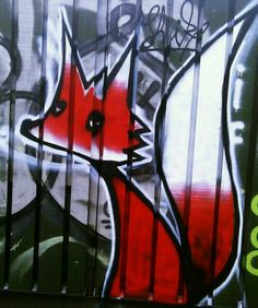 graffiti on the side of a building with red and white fox head painted on it