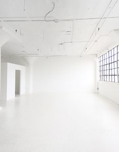 an empty room with white walls and windows